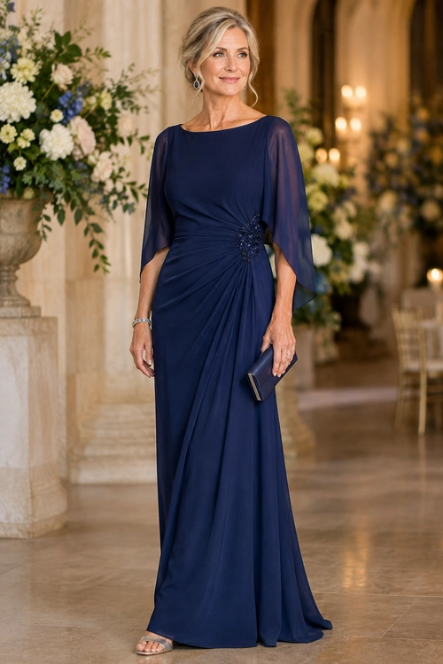 Navy Draped Evening Gown A woman wears a floor-length navy gown with sheer sleeves, gathered draping, a jeweled waist detail, and a matching clutch.
