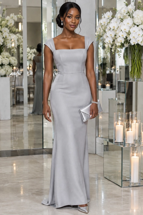 Woman wearing a floor-length silver square-neck gown with cap sleeves, a matching clutch, bracelet, earrings, and pointed heels.